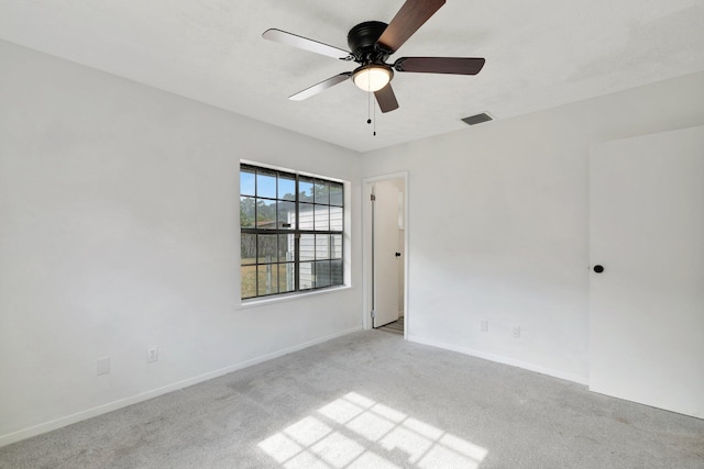 empty room with baseboards, ceiling fan, light carpet, and visible vents