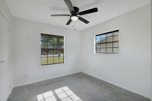 empty room with carpet flooring, a ceiling fan, and baseboards