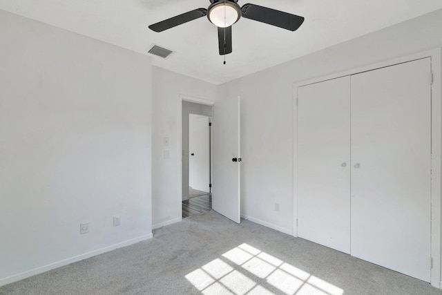 unfurnished bedroom with ceiling fan, light colored carpet, visible vents, baseboards, and a closet