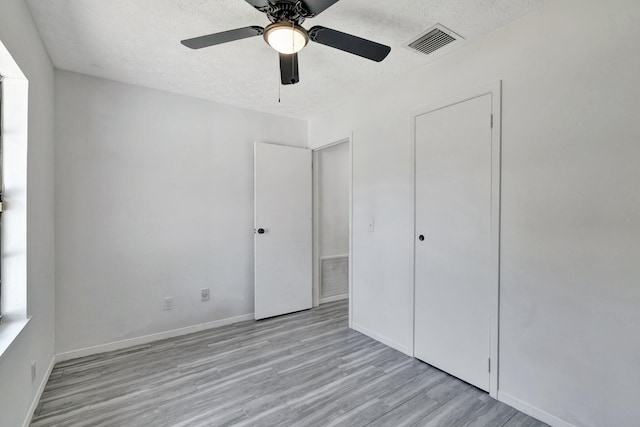unfurnished bedroom with a textured ceiling, wood finished floors, and visible vents