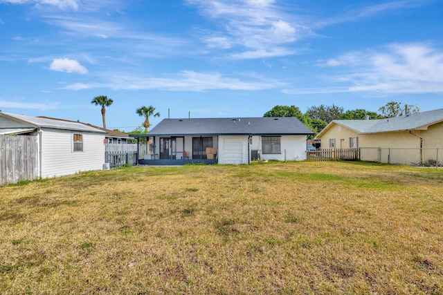 back of house featuring fence, a yard, and a sunroom