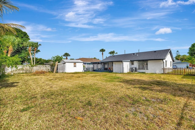 view of yard featuring an outdoor structure, central AC unit, a fenced backyard, and a storage unit