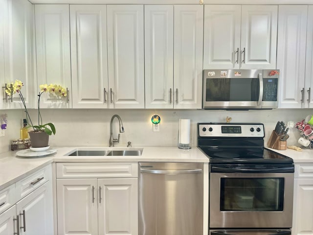 kitchen featuring light countertops, white cabinets, appliances with stainless steel finishes, and a sink