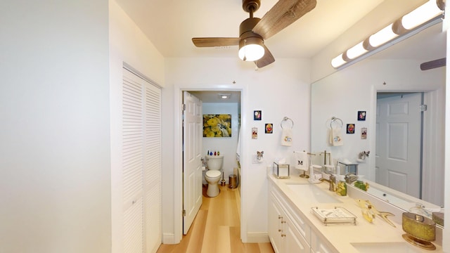 full bathroom with wood finished floors, double vanity, ceiling fan, a sink, and a closet