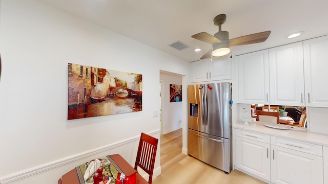 kitchen with light wood finished floors, visible vents, light countertops, stainless steel refrigerator with ice dispenser, and white cabinetry