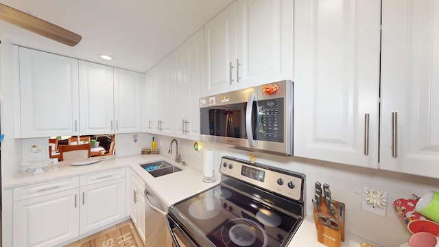 kitchen with recessed lighting, a sink, light countertops, appliances with stainless steel finishes, and white cabinetry