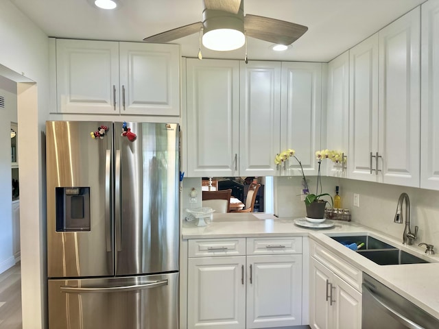 kitchen featuring a sink, appliances with stainless steel finishes, white cabinets, light countertops, and ceiling fan