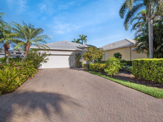 ranch-style house with stucco siding, decorative driveway, and a garage