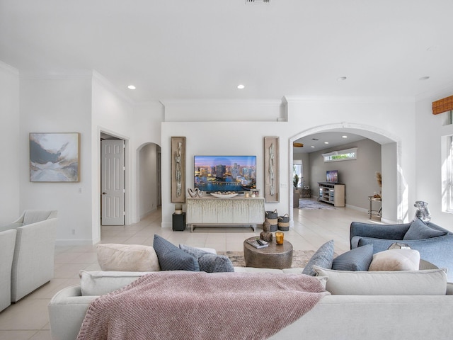 living area with light tile patterned floors, baseboards, recessed lighting, arched walkways, and crown molding