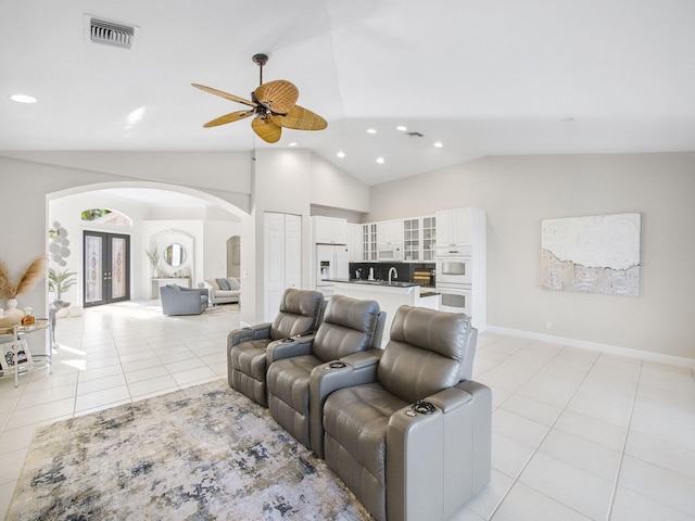 living area with visible vents, arched walkways, light tile patterned floors, ceiling fan, and vaulted ceiling