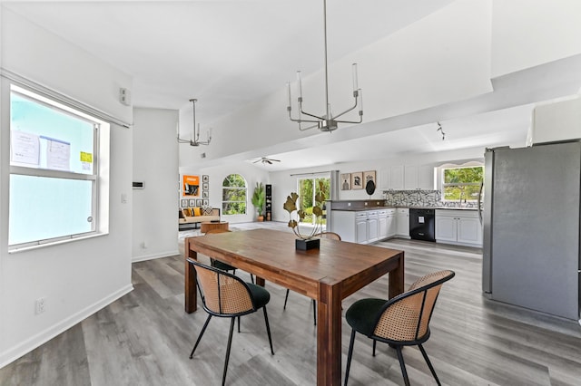 dining space featuring light wood-type flooring, ceiling fan with notable chandelier, baseboards, and a healthy amount of sunlight