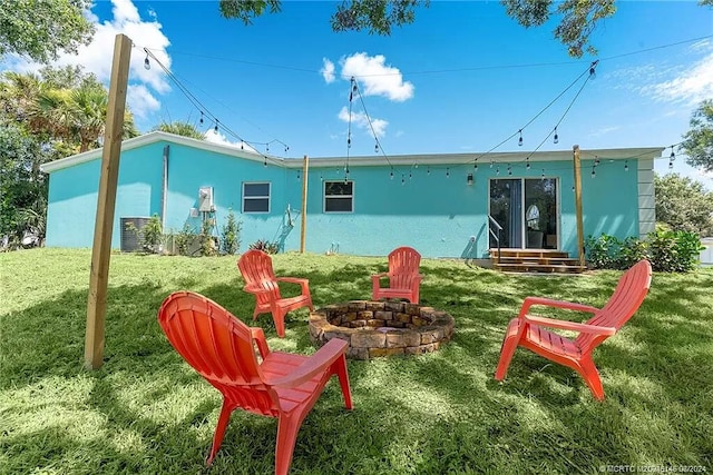 back of property featuring stucco siding, a yard, entry steps, and an outdoor fire pit