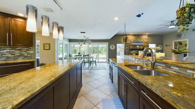 kitchen with visible vents, light tile patterned flooring, a sink, decorative backsplash, and a stone fireplace