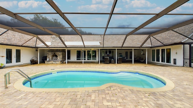 pool featuring french doors, an outdoor stone fireplace, glass enclosure, and a patio area