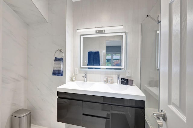 full bathroom with tile walls, vanity, and visible vents
