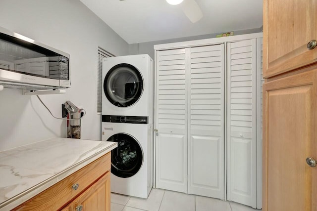washroom with stacked washer / dryer, cabinet space, and light tile patterned flooring