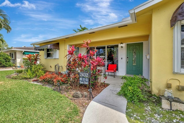 entrance to property featuring a porch and stucco siding