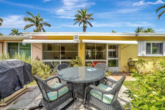 back of property with a patio, outdoor dining space, and stucco siding