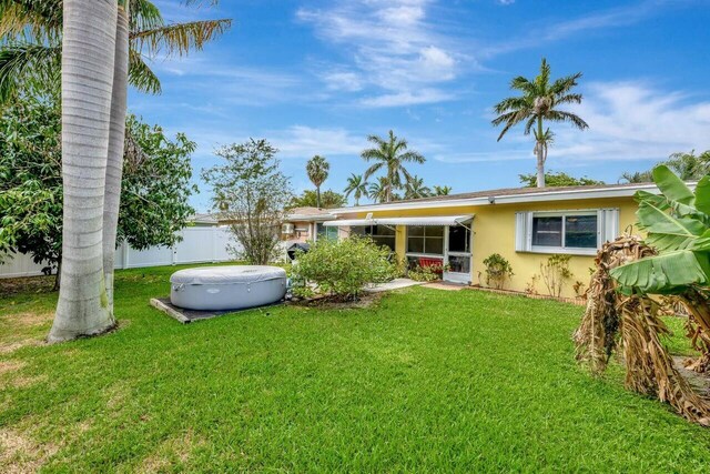 rear view of house featuring stucco siding, a yard, and fence