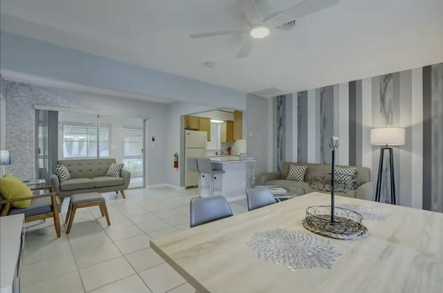interior space with ceiling fan, baseboards, wallpapered walls, and light tile patterned floors