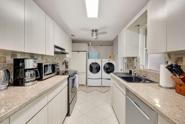 kitchen with a sink, separate washer and dryer, decorative backsplash, appliances with stainless steel finishes, and under cabinet range hood