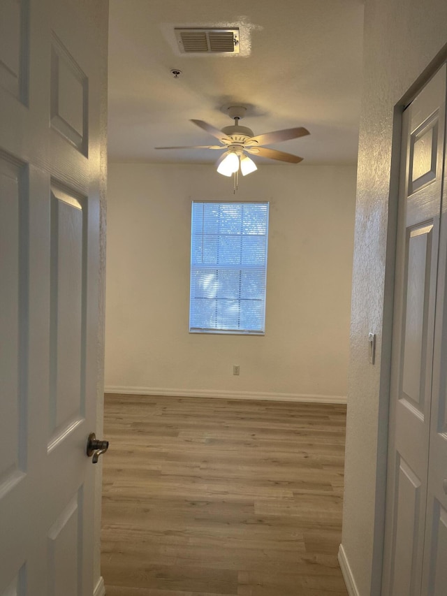 unfurnished room featuring ceiling fan, wood finished floors, visible vents, and baseboards