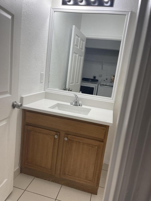 bathroom with vanity, tile patterned floors, a textured wall, and washing machine and clothes dryer