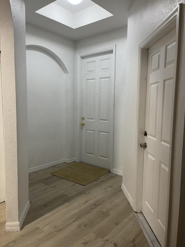 interior space with baseboards, arched walkways, and light wood-style flooring