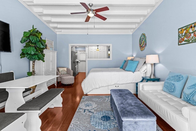 bedroom featuring beam ceiling, wood finished floors, freestanding refrigerator, and ceiling fan