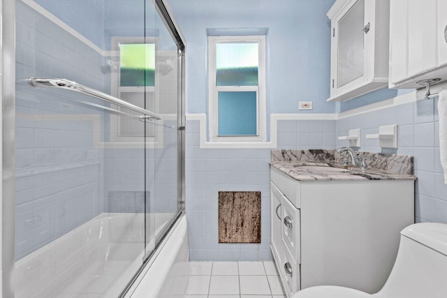 bathroom featuring combined bath / shower with glass door, toilet, tile walls, and tile patterned floors