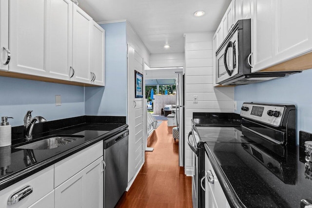 kitchen with a sink, stainless steel appliances, dark wood-style floors, and white cabinetry