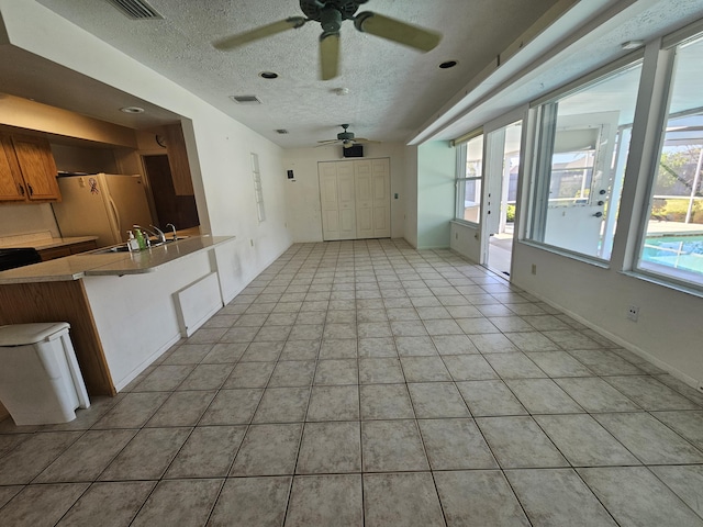 interior space with a sink, visible vents, a textured ceiling, and light tile patterned flooring