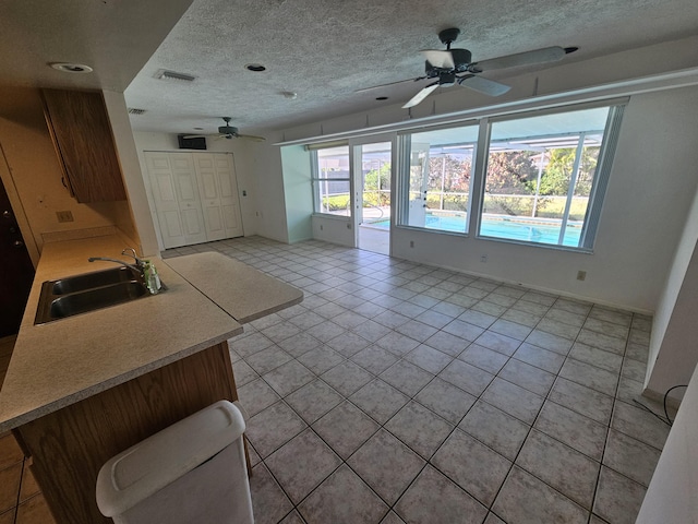 kitchen with visible vents, a sink, light countertops, a textured ceiling, and open floor plan