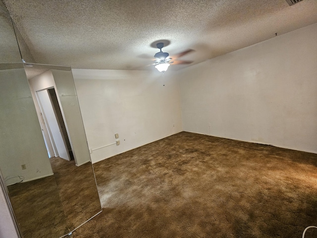 interior space featuring visible vents, dark carpet, a textured ceiling, and ceiling fan