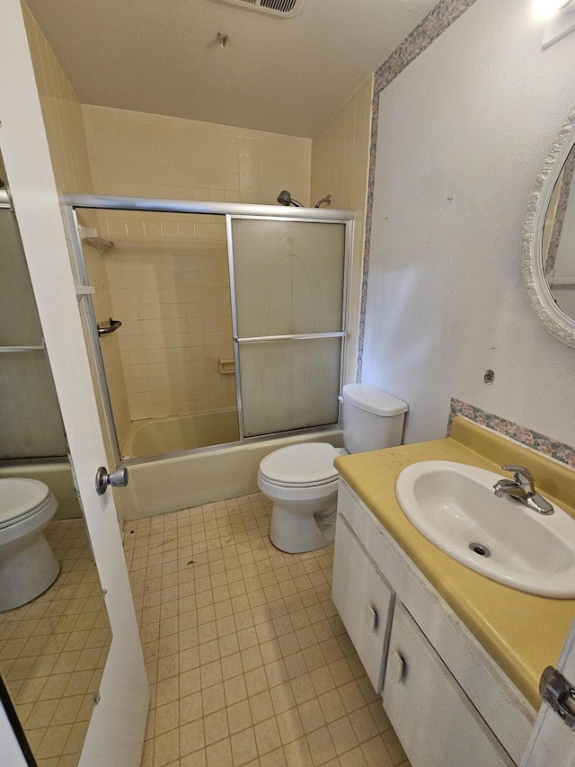 bathroom featuring tile patterned flooring, toilet, vanity, and shower / bath combination with glass door