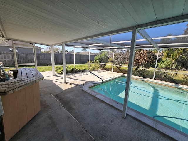 pool featuring glass enclosure, a patio, and a fenced backyard