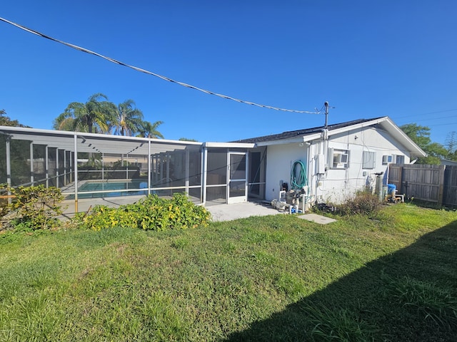 rear view of house featuring stucco siding, a lawn, fence, a fenced in pool, and a lanai