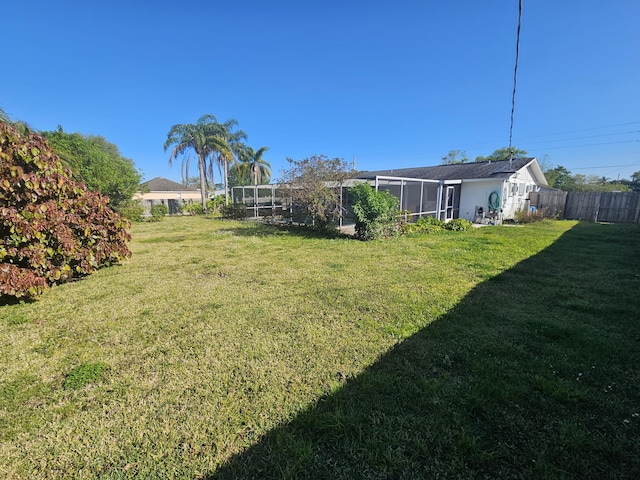 view of yard with glass enclosure and fence