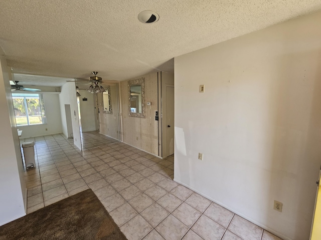 empty room featuring light tile patterned floors, a ceiling fan, and a textured ceiling