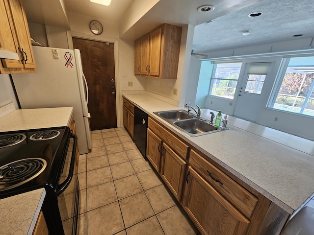 kitchen with brown cabinets, black appliances, light countertops, and a sink