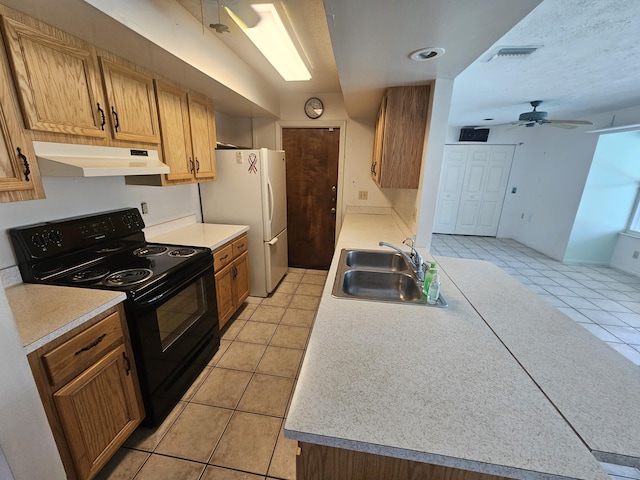 kitchen featuring black / electric stove, visible vents, freestanding refrigerator, a sink, and under cabinet range hood