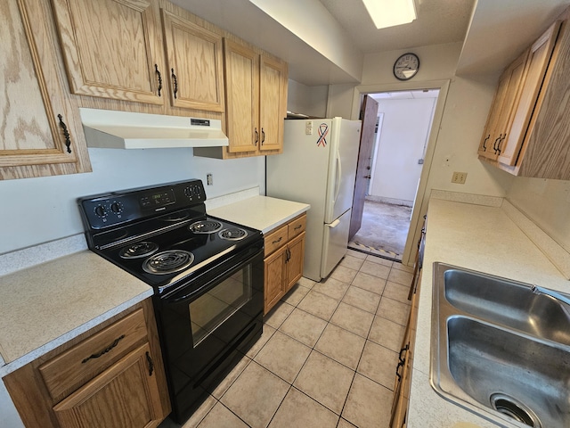 kitchen featuring under cabinet range hood, light countertops, freestanding refrigerator, black electric range oven, and a sink