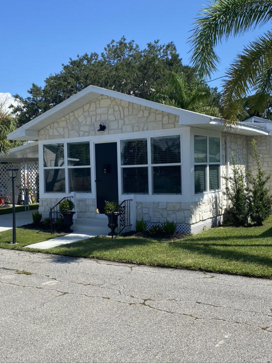 view of front of home with entry steps, a front yard, a carport, and stone siding