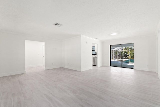 spare room with a textured ceiling, ornamental molding, visible vents, and light wood-type flooring