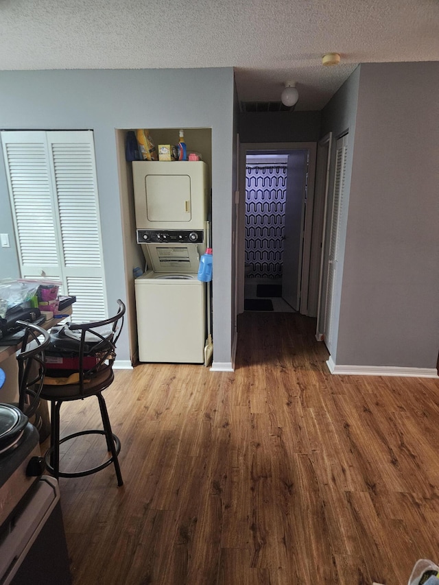 217 SE Village Dr Unit 217, Port Saint Lucie, FL 34952 - kitchen featuring baseboards, a textured ceiling, stacked washing maching and dryer, and wood finished floors