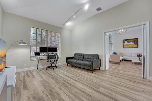 office featuring visible vents, light wood-type flooring, baseboards, and vaulted ceiling