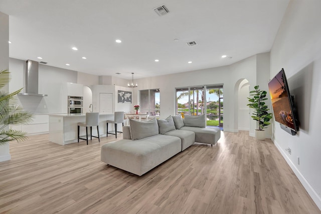 living room with recessed lighting, visible vents, arched walkways, and light wood finished floors