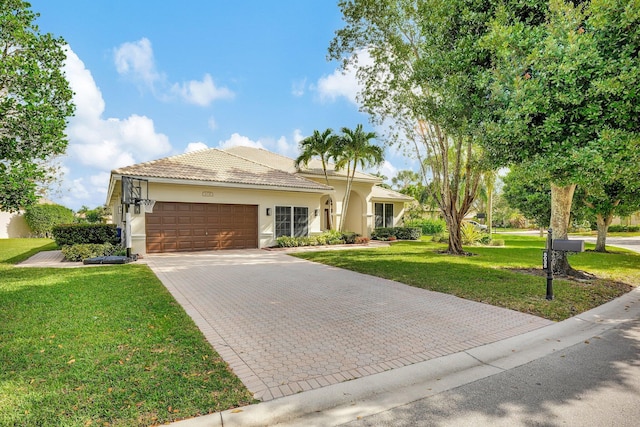 view of front facade featuring a front lawn, a tile roof, stucco siding, decorative driveway, and an attached garage