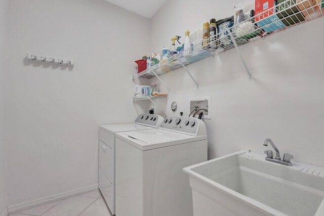 laundry room with baseboards, laundry area, light tile patterned flooring, a sink, and washer and clothes dryer