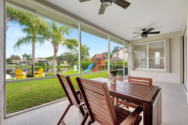 sunroom / solarium featuring a ceiling fan and a water view